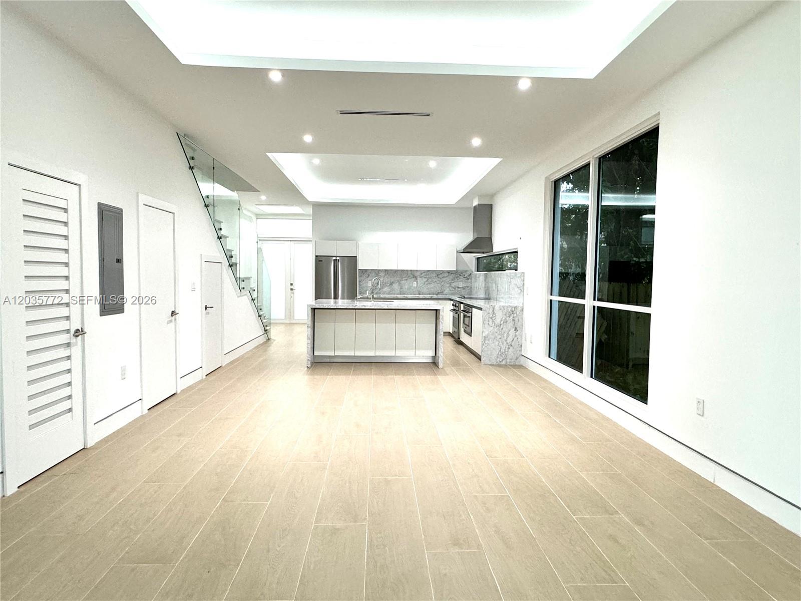 A modern kitchen features a marble island, white cabinetry, and light wood-look tile flooring — 5728 NW 5th Ct # 2, Miami FL 33127, MIAMI, FL