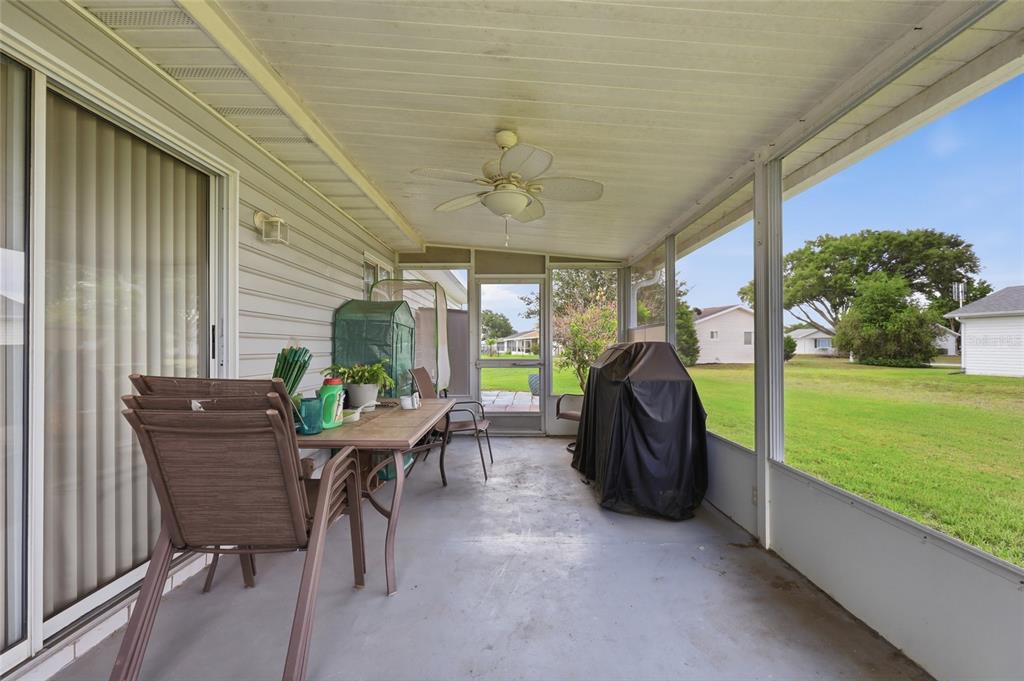 A screened-in patio features a concrete floor, a ceiling fan, and outdoor furniture — 17814 SE 107TH TERRACE, SUMMERFIELD, FL