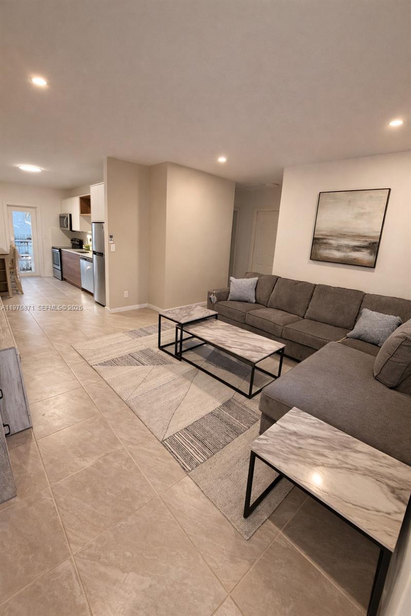 A living room features a grey sectional sofa, marble-topped tables, and an adjacent open kitchen — 7800 NE 10th Ct # 2, Miami FL 33138, MIAMI, FL