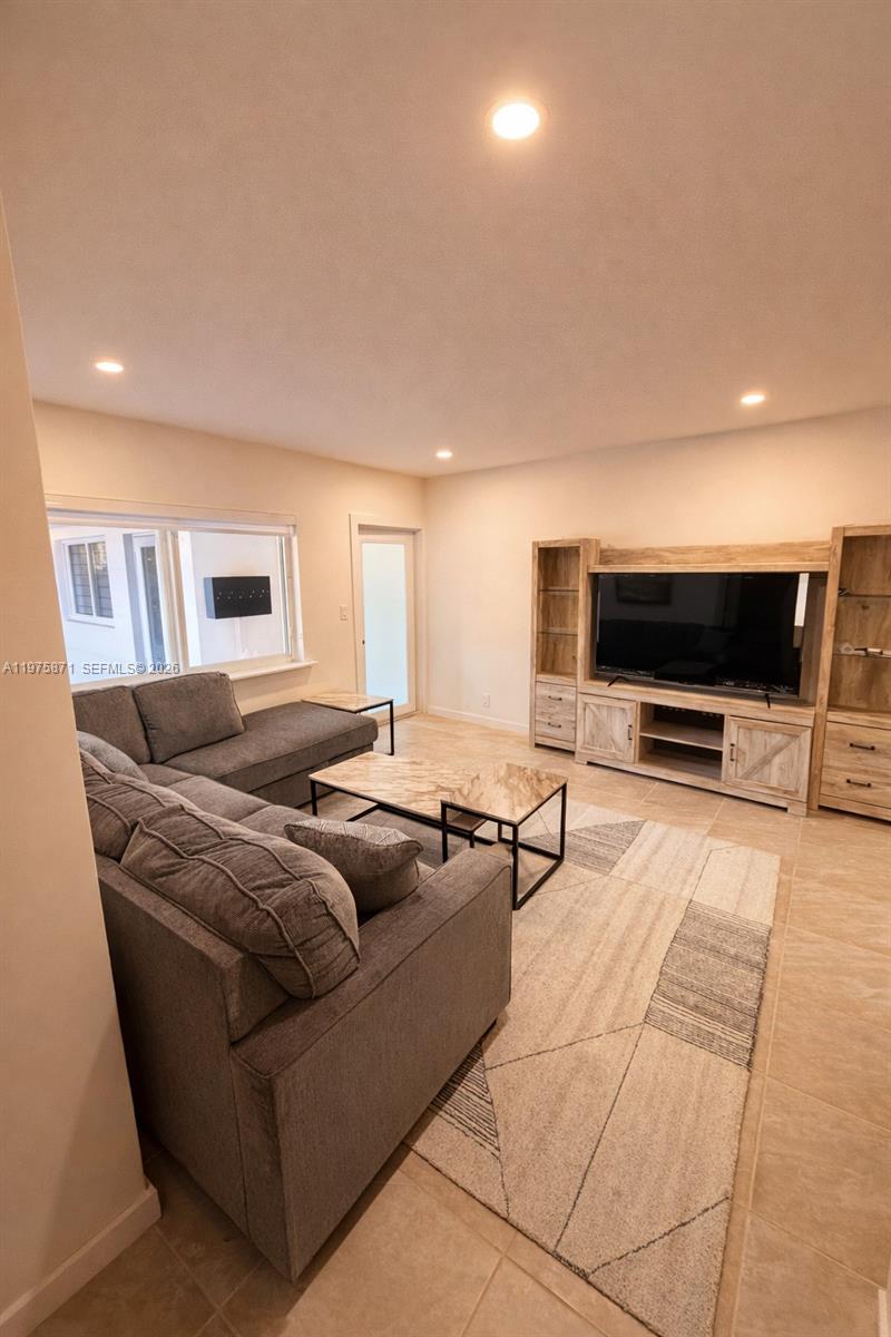 A living room features a grey sectional sofa, a marble coffee table, and a wooden entertainment center — 7800 NE 10th Ct # 2, Miami FL 33138, MIAMI, FL