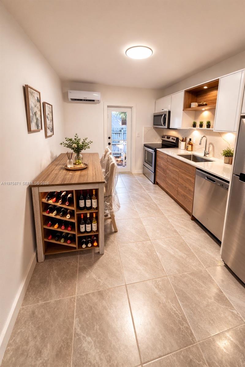 A modern kitchen features wood-toned cabinetry, stainless steel appliances, and a built-in wine rack island — 7800 NE 10th Ct # 2, Miami FL 33138, MIAMI, FL