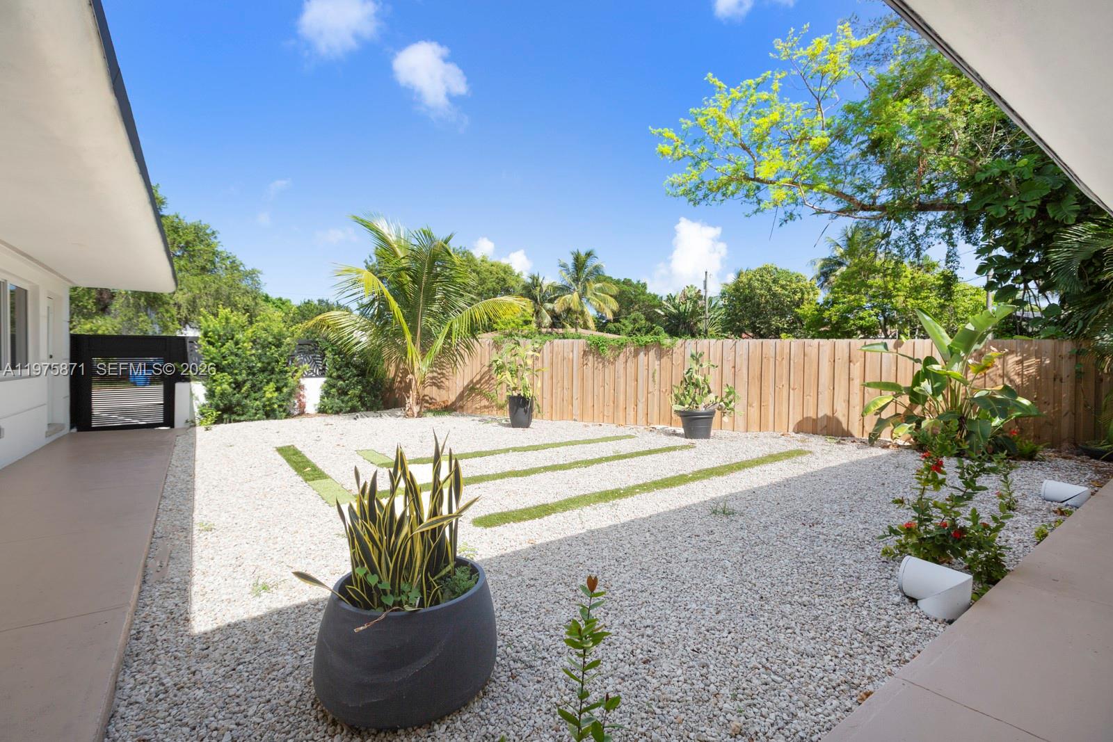 A backyard features a gravel ground cover, artificial grass strips, potted plants, and a wooden fence — 7800 NE 10th Ct # 2, Miami FL 33138, MIAMI, FL