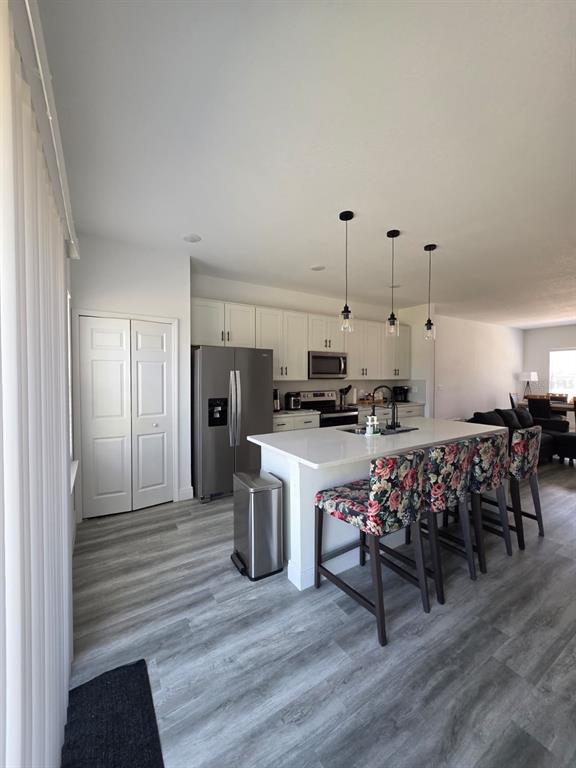 A kitchen features white cabinets, stainless steel appliances, a center island, and floral bar stools — 14886 SW 43RD COURT, OCALA, FL