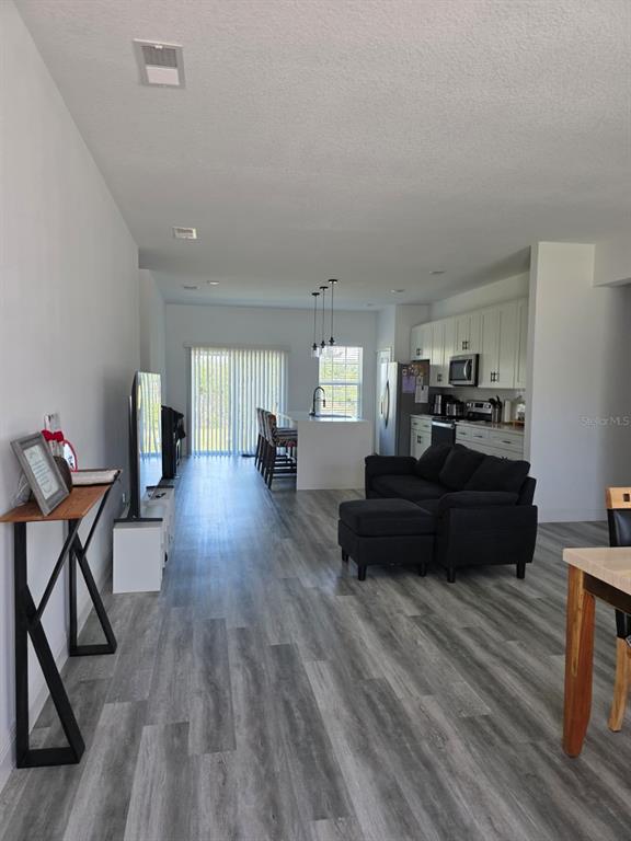 An open-concept living room and kitchen feature gray wood-look flooring and white cabinetry — 14886 SW 43RD COURT, OCALA, FL