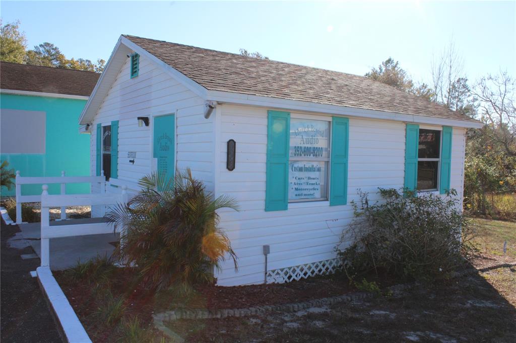 A small white building with teal shutters and a sign advertising custom audio installations — 5134 PLYNA STREET, SPRING HILL, FL