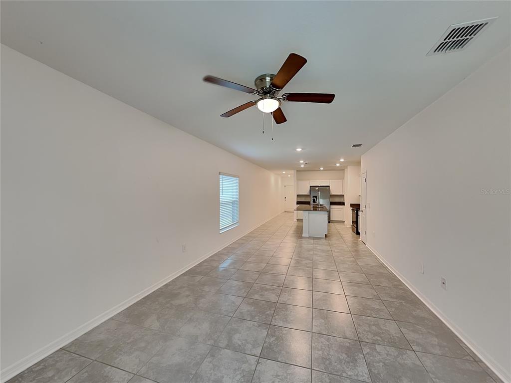 An open-concept living and kitchen area features light gray tile flooring and a ceiling fan — 4273 BABBLING BROOK WAY, KISSIMMEE, FL