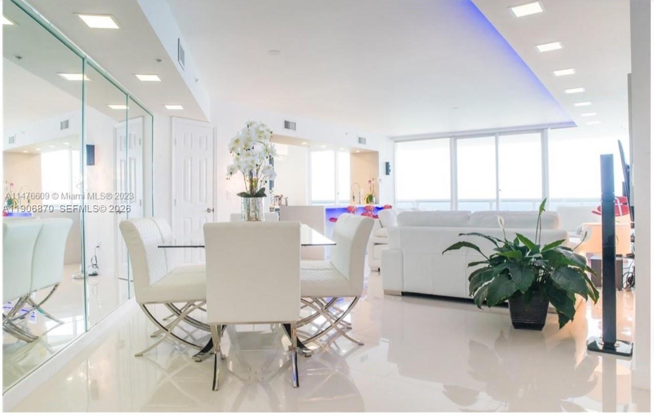 A bright, modern dining and living area features white furniture, tiled floors, and floor-to-ceiling windows — 6301 Collins Ave # 1402, Miami Beach FL 33141, MIAMI BEACH, FL