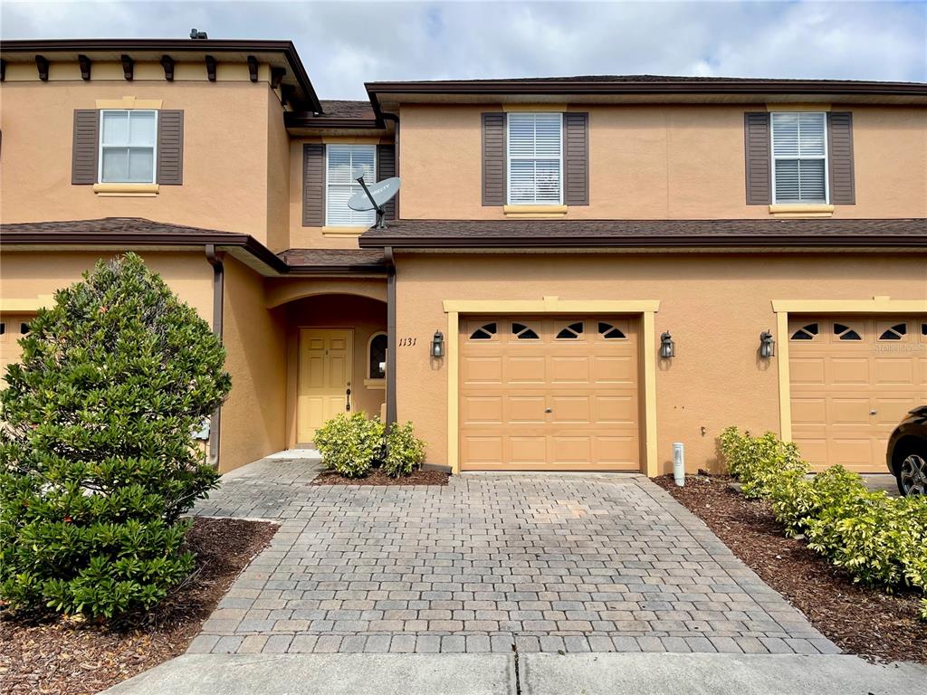 A two-story townhouse exterior features a paved driveway, a garage, and a recessed front entrance — 1131 LONG OAK WAY, SANFORD, FL