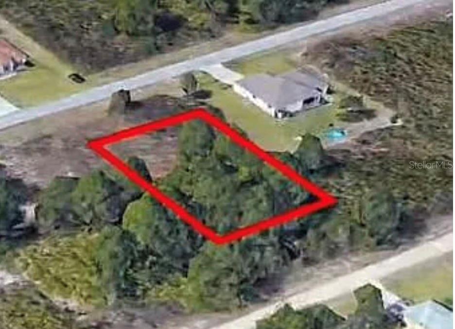 An aerial view shows a vacant, tree-covered rectangular lot outlined in red near a road — 720 PEACOCK AVENUE, LEHIGH ACRES, FL