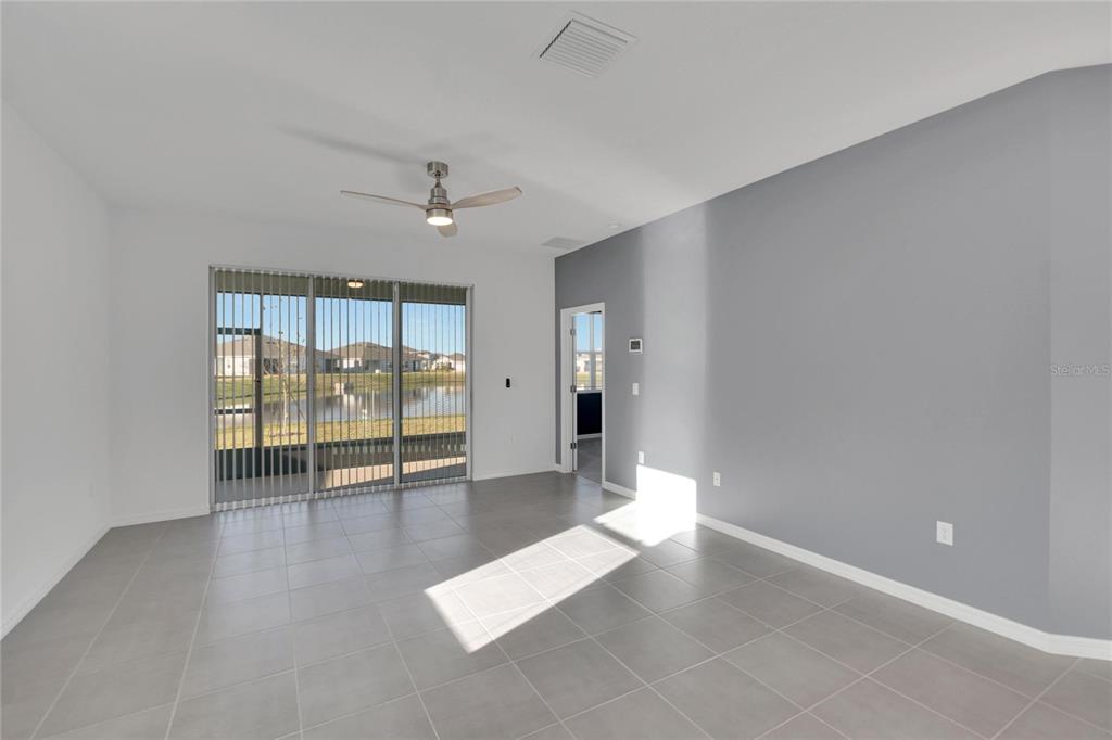 A bright room with gray tile flooring, a ceiling fan, and sliding glass doors overlooking water — 3329 SHADY SUNRISE LOOP, PLANT CITY, FL