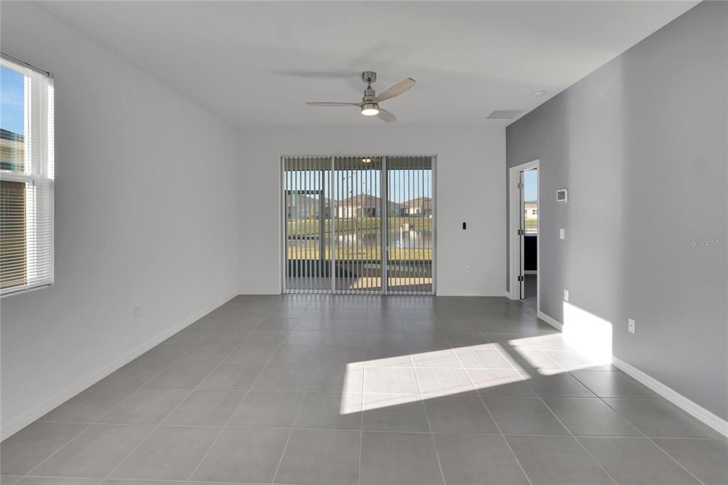 A living room with gray tile flooring, white walls, a ceiling fan, and sliding glass doors — 3329 SHADY SUNRISE LOOP, PLANT CITY, FL
