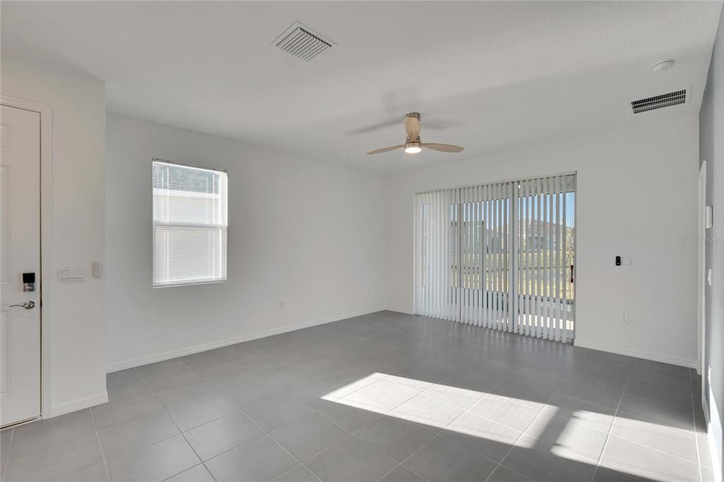 An empty room with gray tile flooring, a ceiling fan, and sliding glass patio doors — 3329 SHADY SUNRISE LOOP, PLANT CITY, FL