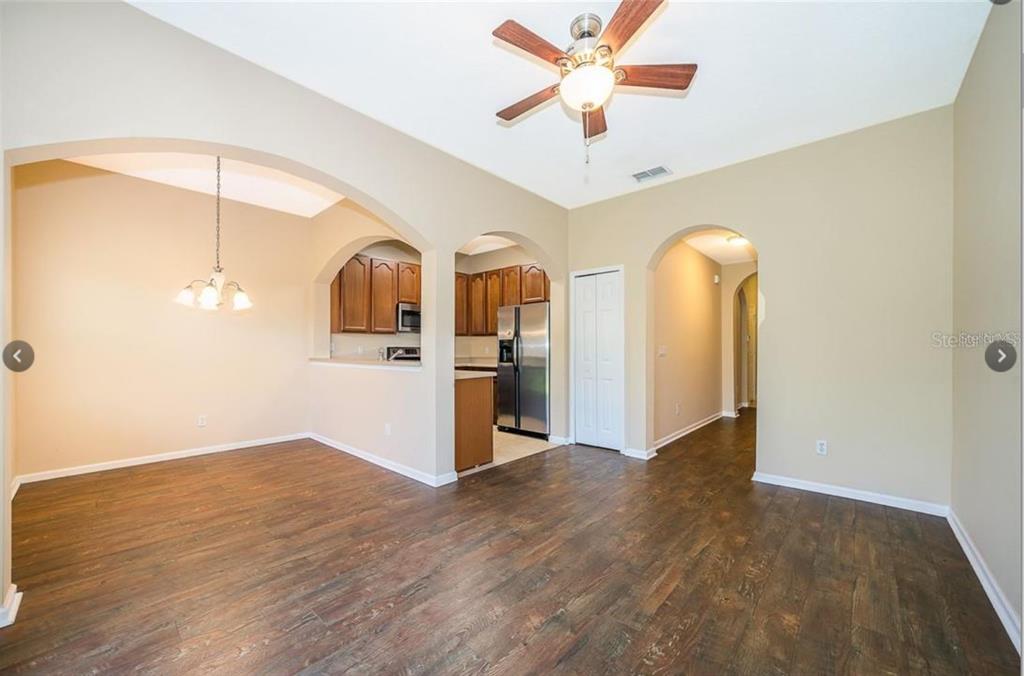 An open-concept living and dining area features wood-look flooring, arched doorways, and a ceiling fan — 16432 CEDAR CREST DRIVE, ORLANDO, FL