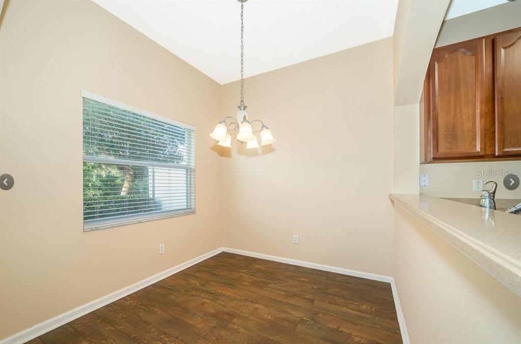 A dining area with wood-look flooring, a chandelier, and a window with blinds — 16432 CEDAR CREST DRIVE, ORLANDO, FL