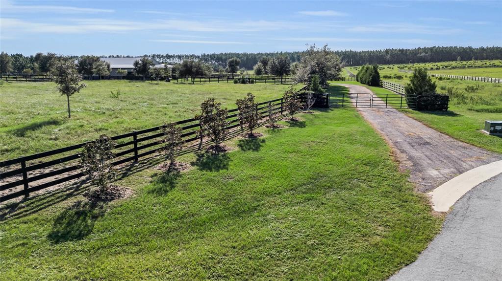 An aerial view shows a metal-roofed building with a covered porch and adjacent fenced pastures — 9722 NW 26TH STREET, WILDWOOD, FL