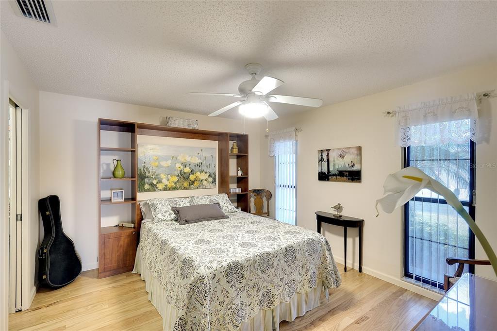 A bedroom features a queen bed with a built-in headboard, wood flooring, and a ceiling fan — 6004 VIVIENDA DRIVE UNIT 8, BRADENTON, FL