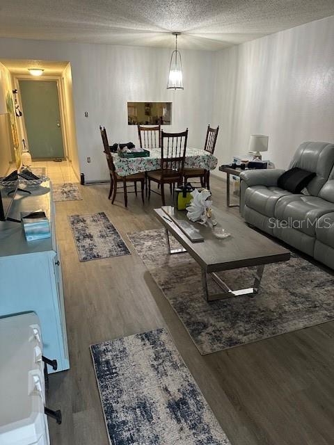 An open-concept living and dining area features light wood-look flooring and a gray sofa — 4079 LAKE BAYSHORE DRIVE UNIT 308, BRADENTON, FL