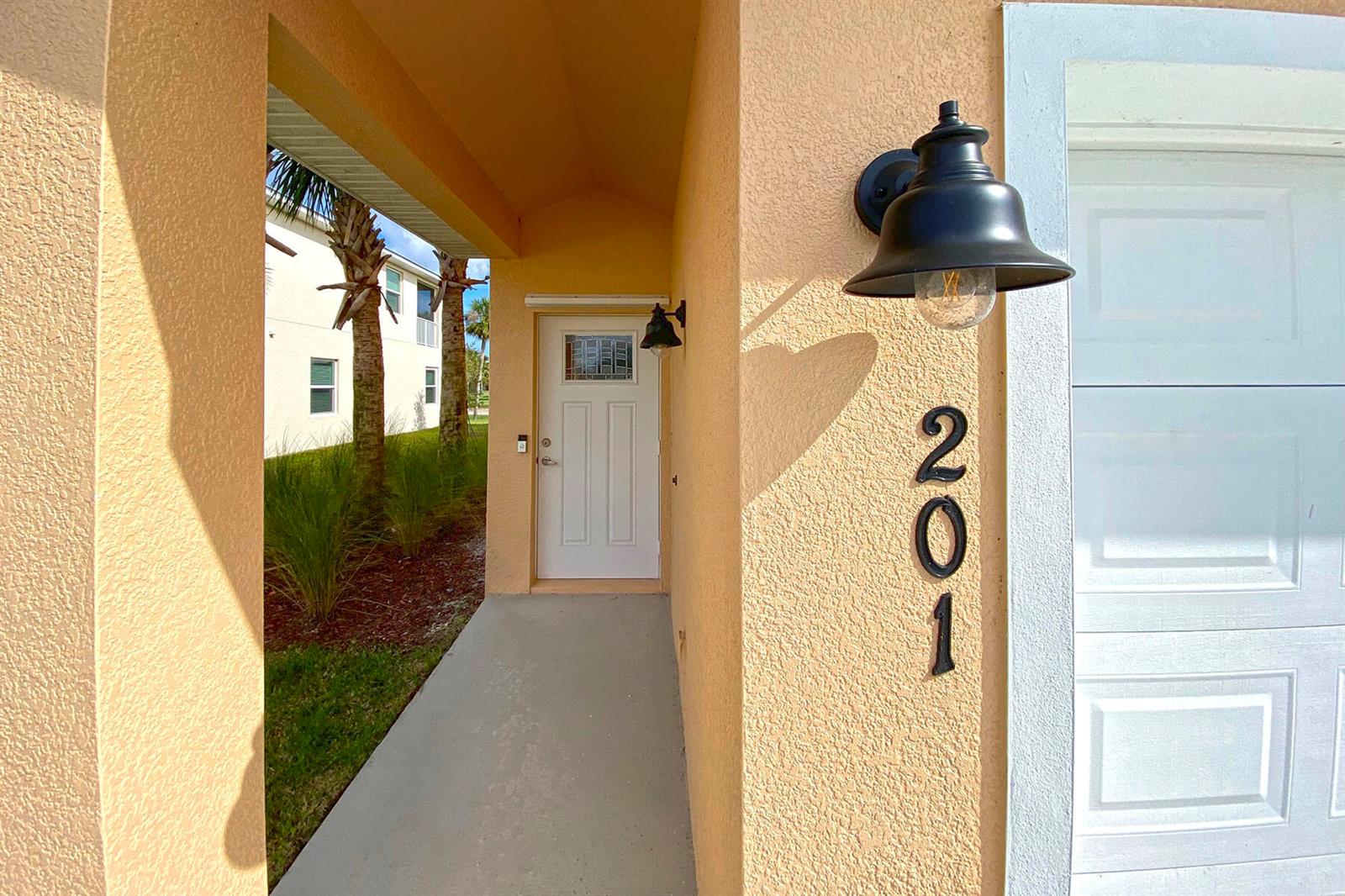 The exterior entrance features a white door, a black wall lamp, and house number 201 — 3951 Playa Del Sol Drive # 201, Rockledge FL 32955, ROCKLEDGE, FL