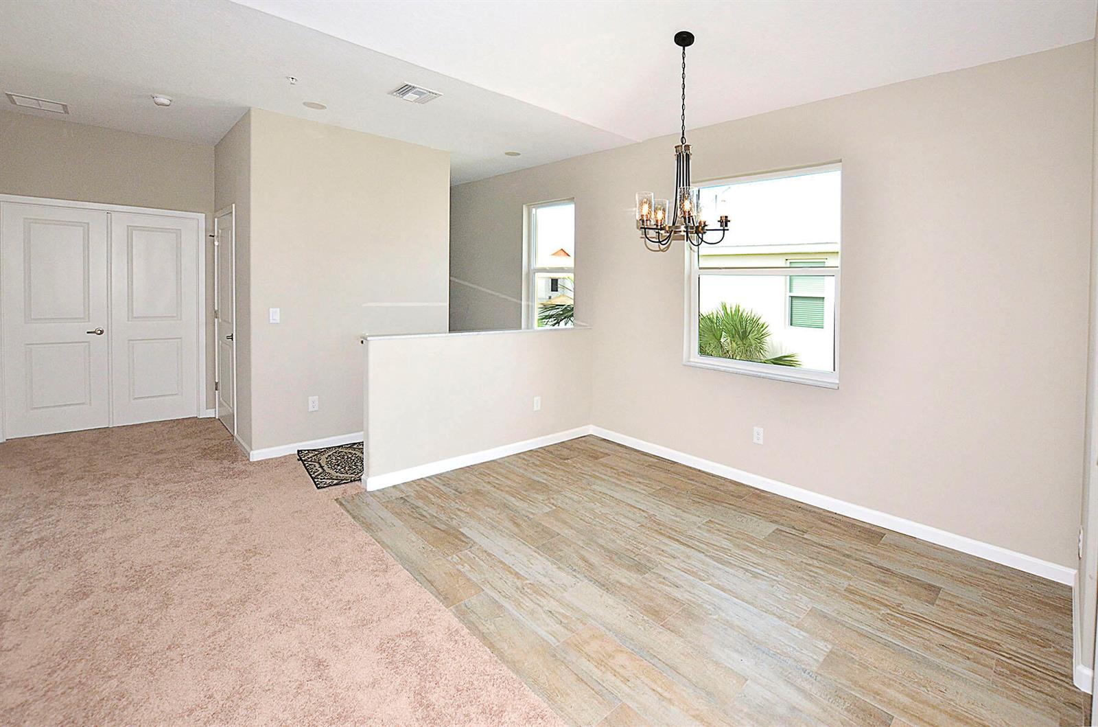 A dining area features wood-look tile flooring, a chandelier, and a partial wall divider — 3951 Playa Del Sol Drive # 201, Rockledge FL 32955, ROCKLEDGE, FL