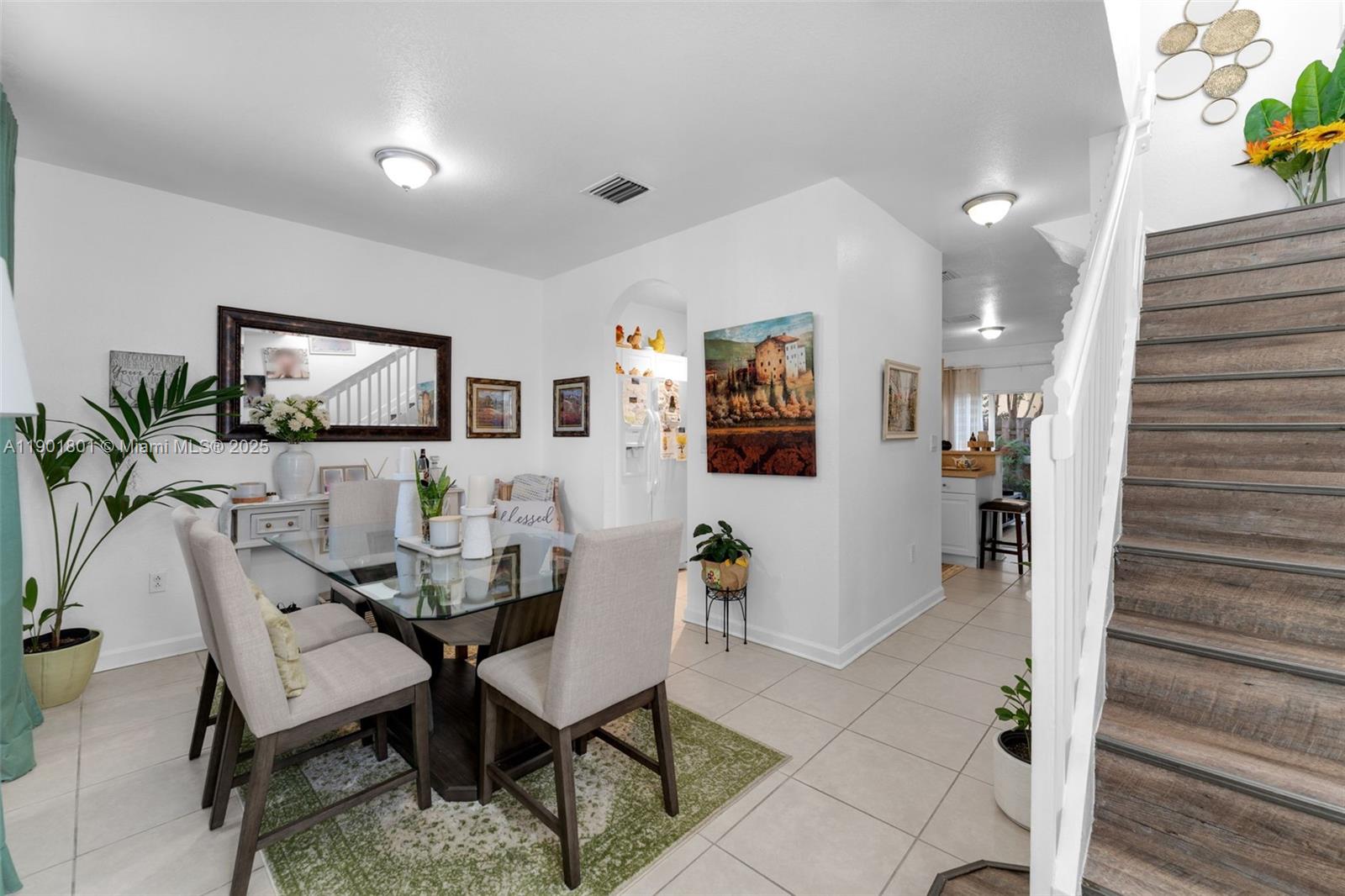 A dining area with a glass table and chairs sits next to a wooden staircase — 1595 NE 33rd Rd # 3, Homestead FL 33033, HOMESTEAD, FL
