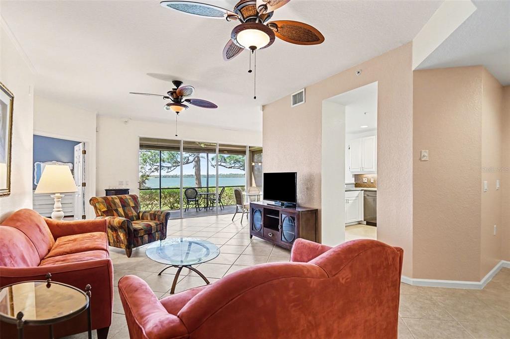 A living room with tile floors, two red sofas, and a view of the water — 4696 CLUB DRIVE UNIT 102, PORT CHARLOTTE, FL