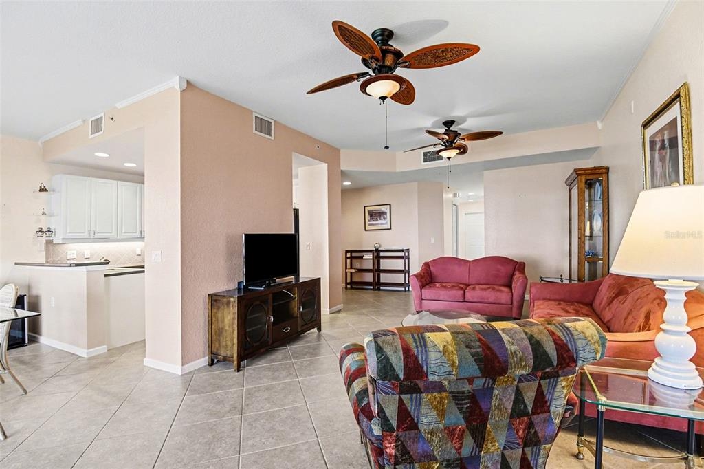 A living room features tile floors, two ceiling fans, and a view into the kitchen — 4696 CLUB DRIVE UNIT 102, PORT CHARLOTTE, FL