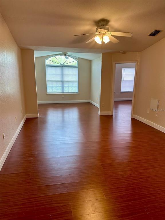An empty living area with wood-look flooring, a ceiling fan, and a large arched window — 3373 S KIRKMAN ROAD UNIT 939, ORLANDO, FL