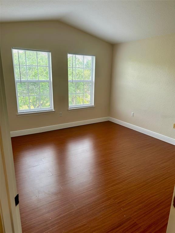 An empty room features wood-look flooring, two windows with blinds, and light-colored walls — 3373 S KIRKMAN ROAD UNIT 939, ORLANDO, FL