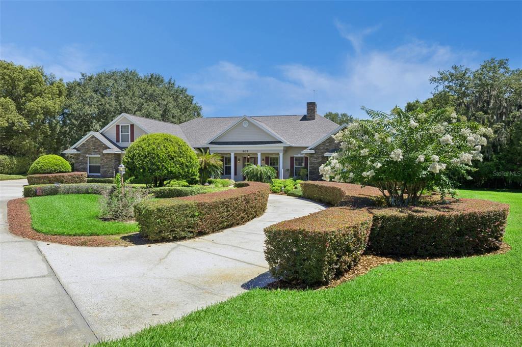 A one-story house with a stone facade, a curved driveway, and manicured hedges — 605 OLD MOUNT DORA ROAD, EUSTIS, FL