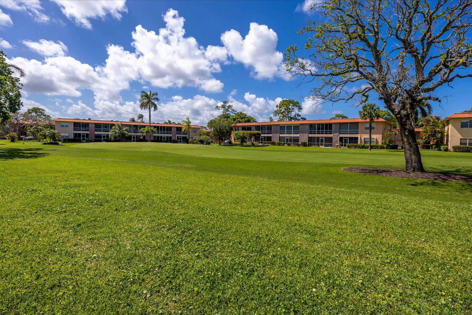 A large green lawn sits in front of two multi-story apartment buildings under a sky — 1943 SW Palm City Road # d, Stuart FL 34994, STUART, FL