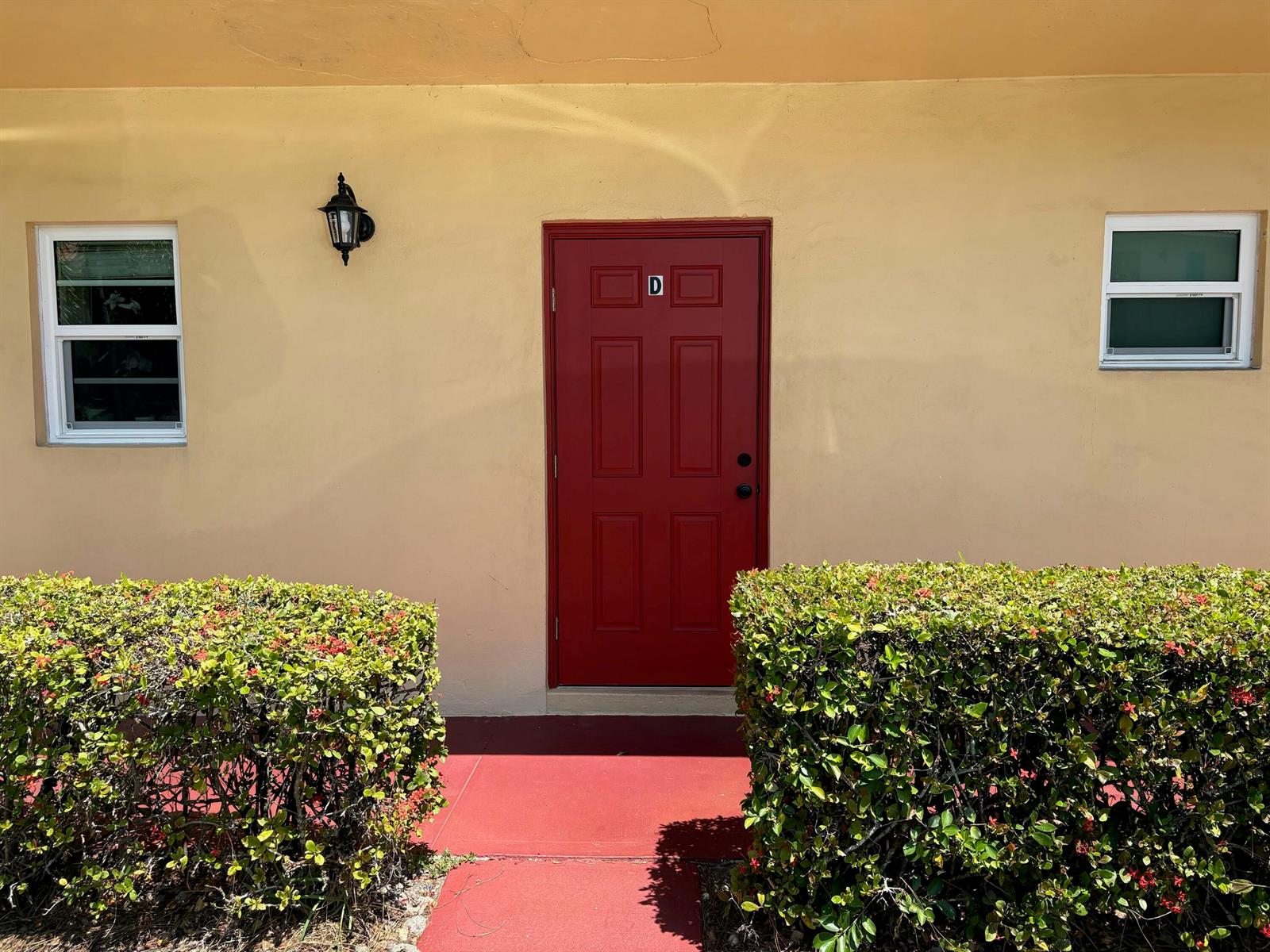 A red front door labeled D is centered between two windows on a yellow wall — 1943 SW Palm City Road # d, Stuart FL 34994, STUART, FL