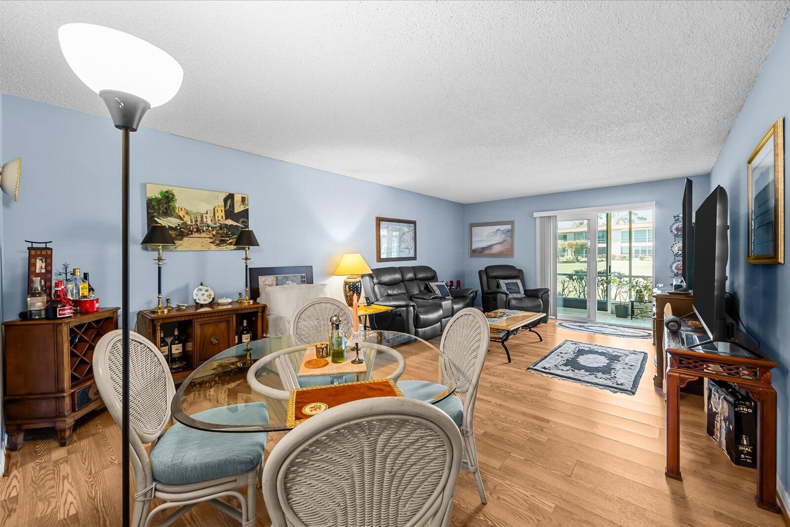 A living and dining area with light blue walls, wood flooring, and a glass-topped table — 1943 SW Palm City Road # d, Stuart FL 34994, STUART, FL