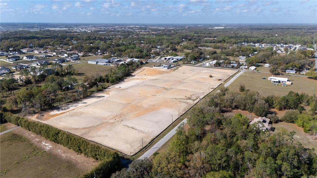 An aerial view shows a large, cleared rectangular plot of land surrounded by trees and houses — 32784 DUNNE ROAD, SAN ANTONIO, FL