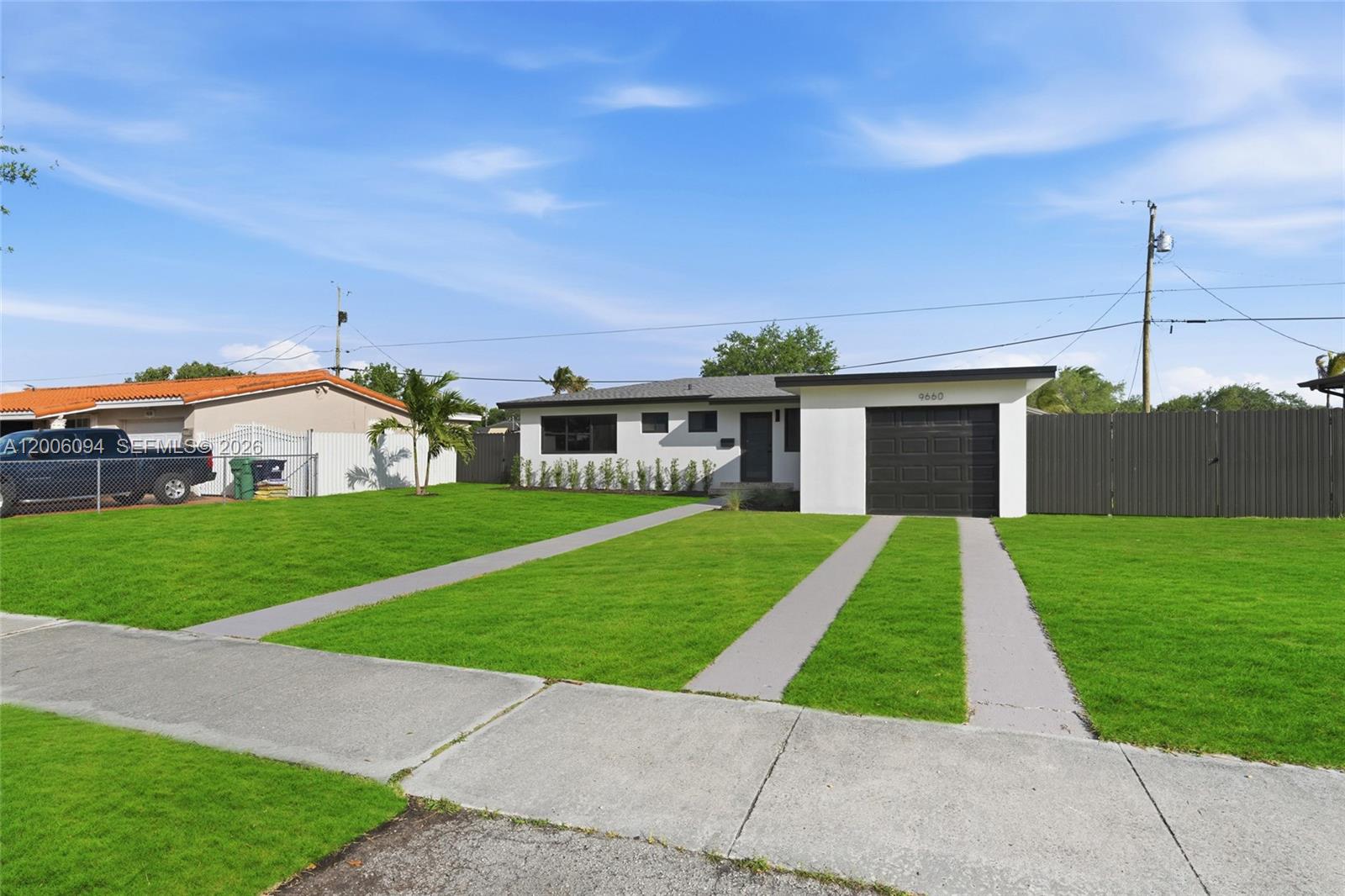 A single-story house with a white exterior, dark garage door, and a green lawn — 9660 Dominican Dr, Cutler Bay FL 33189, CUTLER BAY, FL