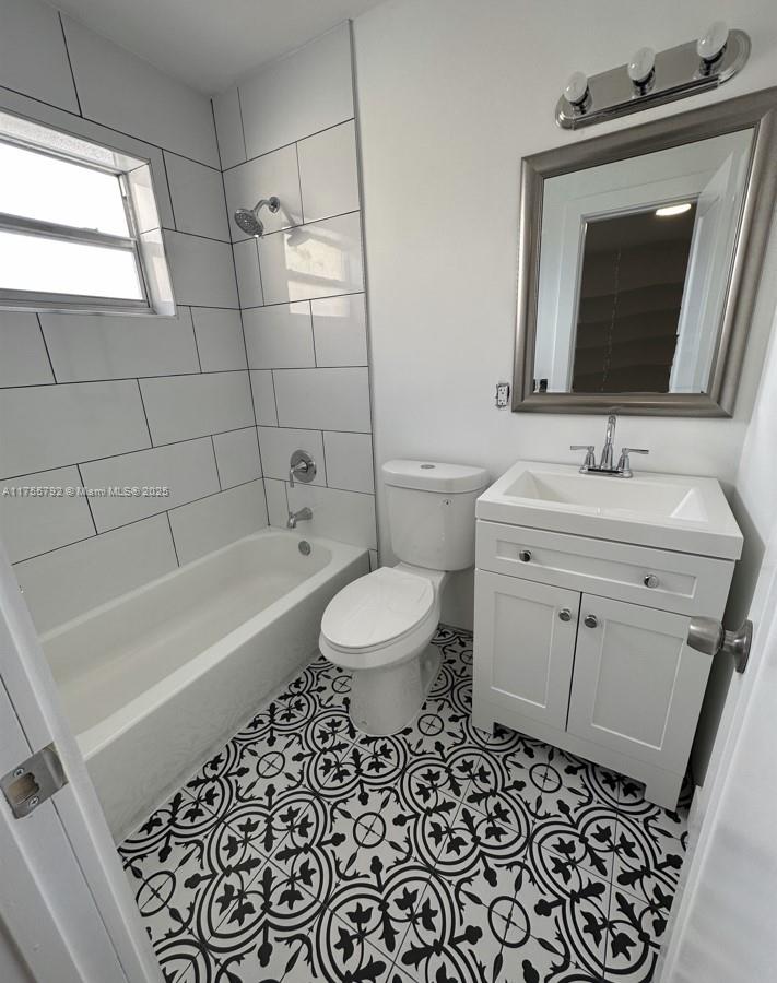 A bathroom features a white vanity, a toilet, a bathtub with white tiles, and patterned flooring — 25 W 6th St # 25, Hialeah FL 33010, HIALEAH, FL