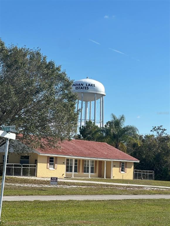 A single-story yellow house with a red roof sits beneath a large water tower — 0 PINNATA DRIVE, LAKE WALES, FL