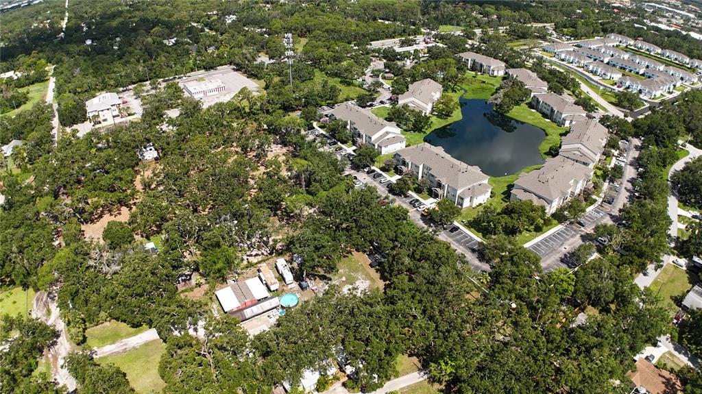 An aerial view shows apartment buildings, a pond, and wooded areas with residential properties — 0 51ST STREET, SARASOTA, FL