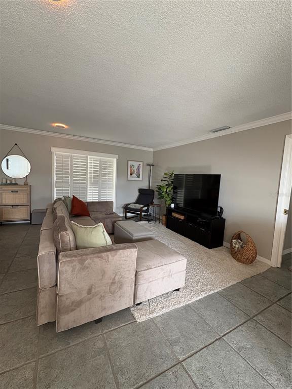 A living room features a large sectional sofa, a television on a stand, and tile flooring — 1500 GAY ROAD UNIT 20D, WINTER PARK, FL