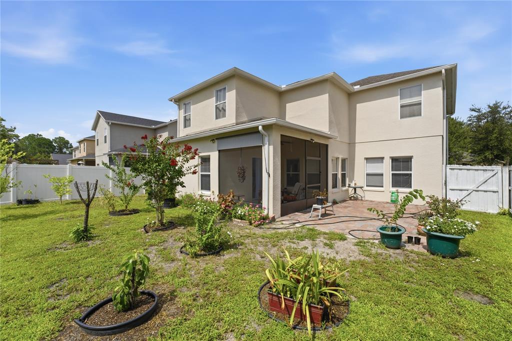 The exterior of a two-story house features a screened-in patio and a fenced backyard — 10114 OAK CREST ROAD, ORLANDO, FL
