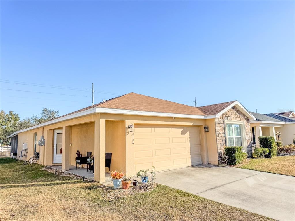 A single-story house with a tan stucco exterior, stone accents, and a two-car garage — 2128 BRETTON RIDGE BOULEVARD, WINTER HAVEN, FL