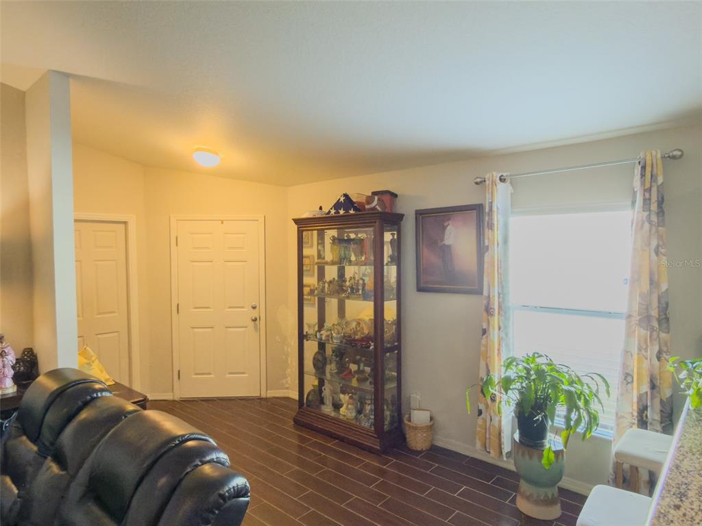 A living room with dark wood floors, a glass display cabinet, and a front door — 2128 BRETTON RIDGE BOULEVARD, WINTER HAVEN, FL