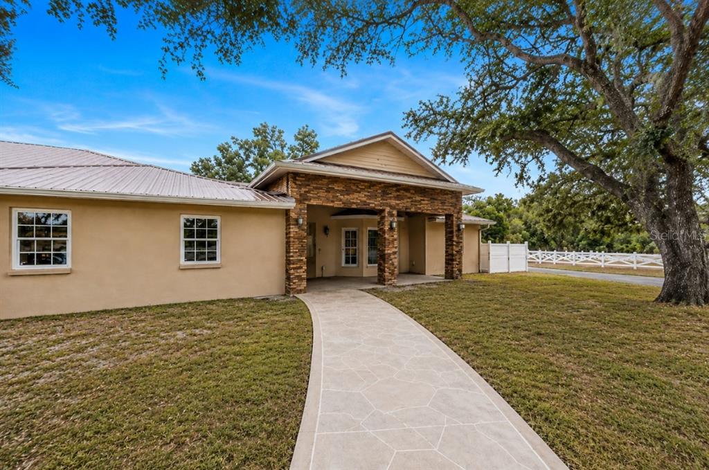 A tan house with a stone-accented entryway and a paved walkway leading to the door — 1160 WAGON WHEEL DRIVE, SARASOTA, FL