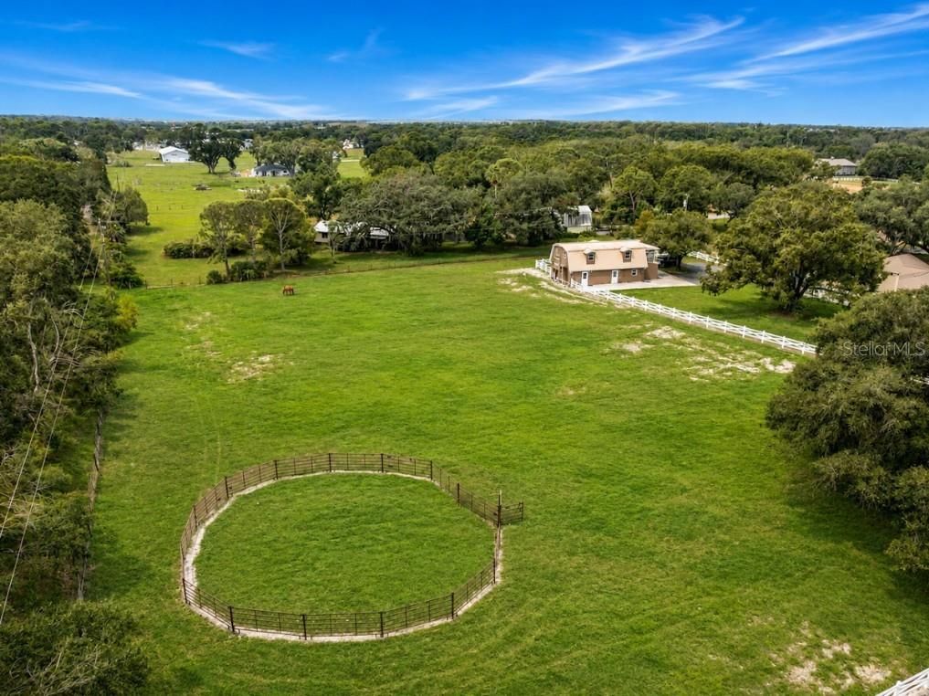 An aerial view of a grassy pasture featuring a round pen and a two-story barn — 1160 WAGON WHEEL DRIVE, SARASOTA, FL