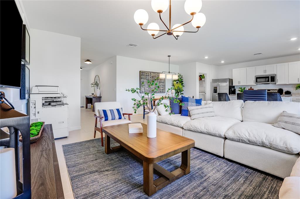 A hallway with light tile flooring leads to a window, with carpeted stairs on the left — 18047 MELLON STREET, PARRISH, FL