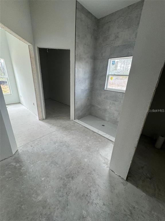An unfinished bathroom features a tiled walk-in shower with a window and concrete flooring — 13449 SW 60TH AVENUE ROAD, OCALA, FL