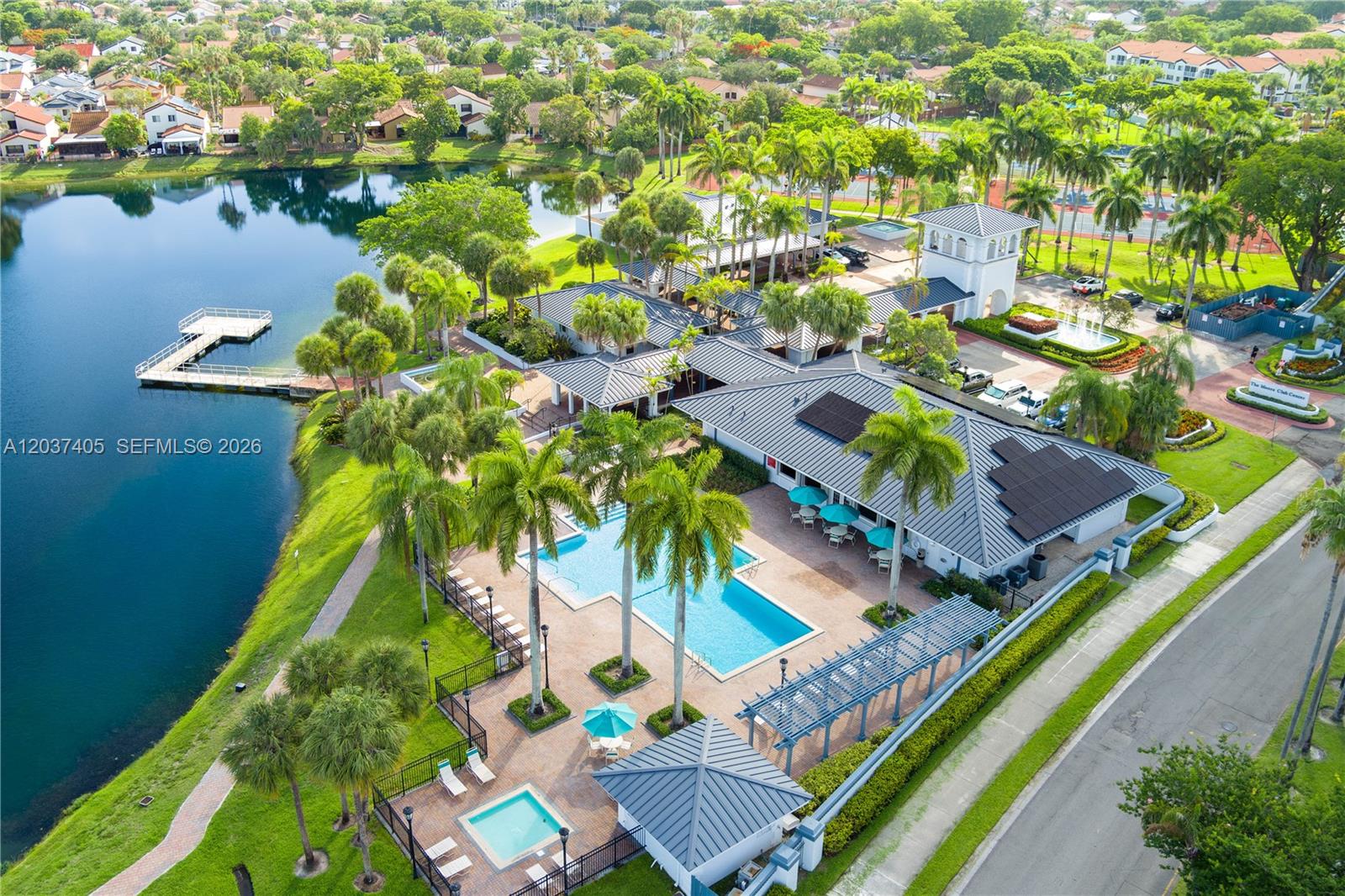 An aerial view shows a community clubhouse with a pool, spa, and lakefront dock — 18226 Mediterranean Blvd # 16, Hialeah FL 33015, HIALEAH, FL