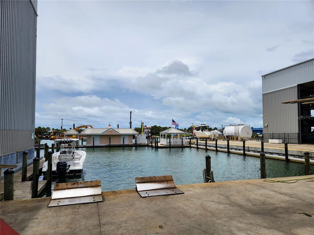 A boat docked at a marina with a gazebo and industrial buildings in the background — 100 CIRCUIT ROAD UNIT N12, NOKOMIS, FL