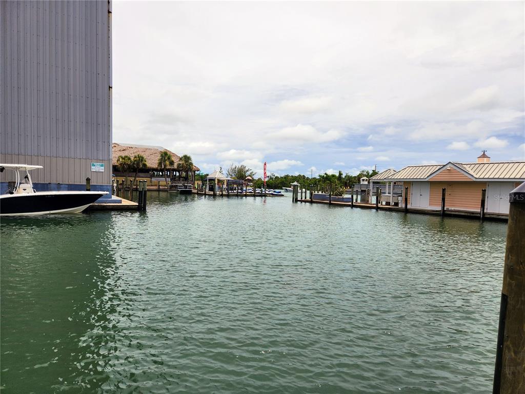 A view of a marina with a boat docked beside a large metal building — 100 CIRCUIT ROAD UNIT N12, NOKOMIS, FL