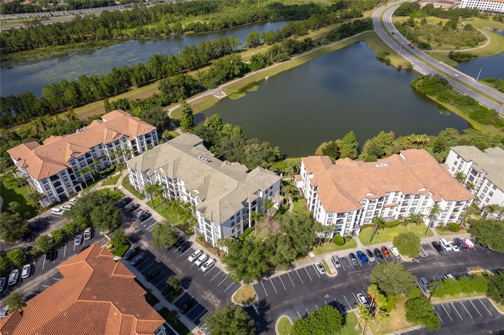 An aerial view shows several multi-story apartment buildings surrounded by parking lots and a lake — 4102 BREAKVIEW DRIVE UNIT 40203, ORLANDO, FL