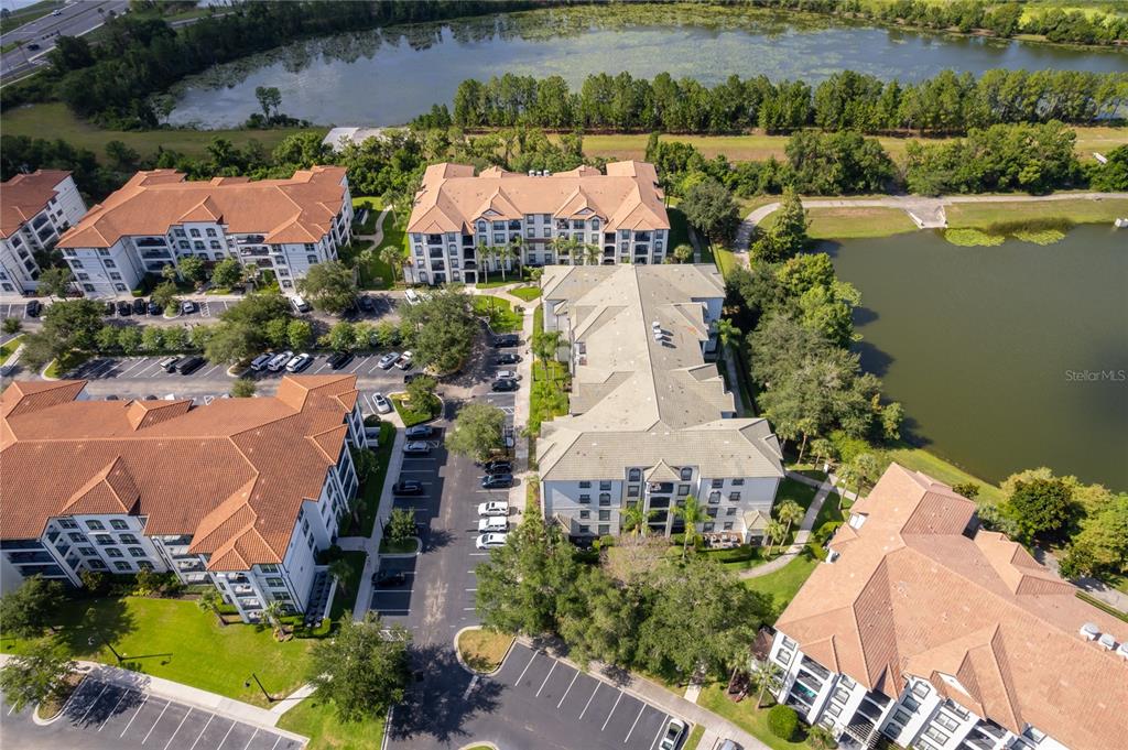 An aerial view shows several multi-story apartment buildings surrounded by parking lots and a lake — 4102 BREAKVIEW DRIVE UNIT 40203, ORLANDO, FL
